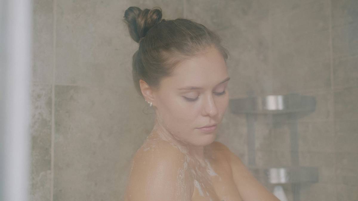 Woman applying gentle shower gel during her shower skin care routine